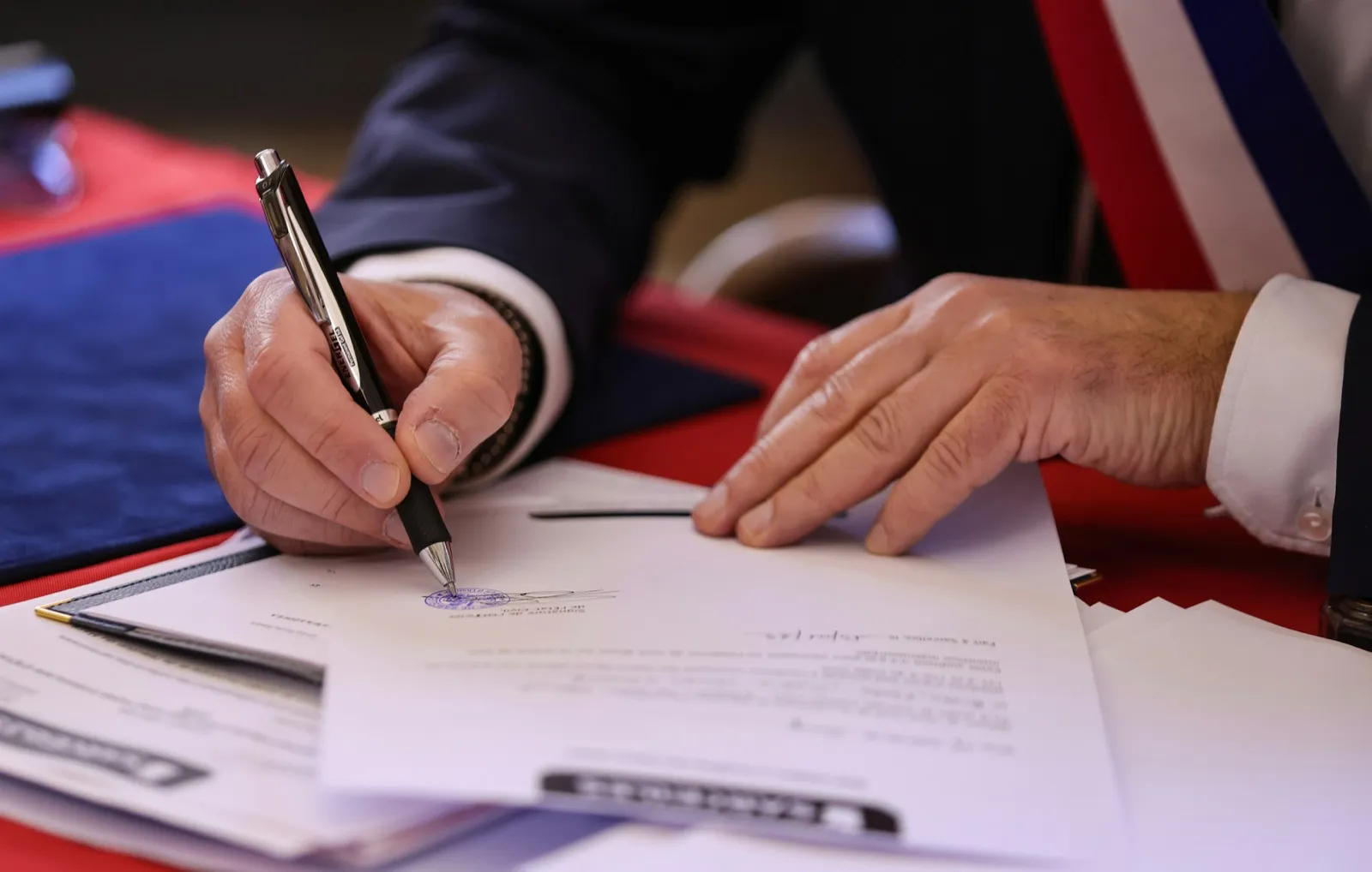 A person signing a will document with a pen at an attorney's office